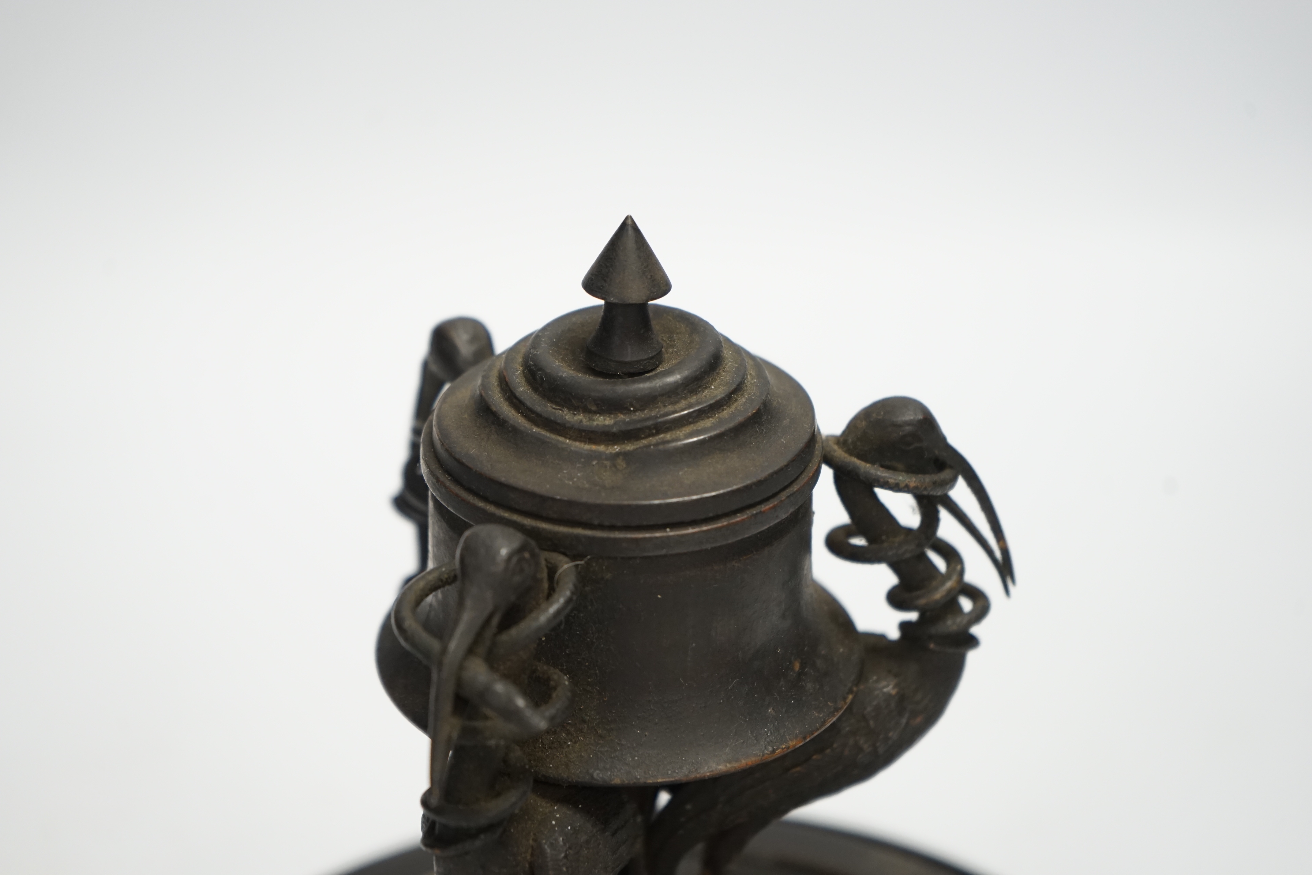 A late 19th century patinated metal inkwell, modelled with three cranes on an ebonised pine base, 18cm